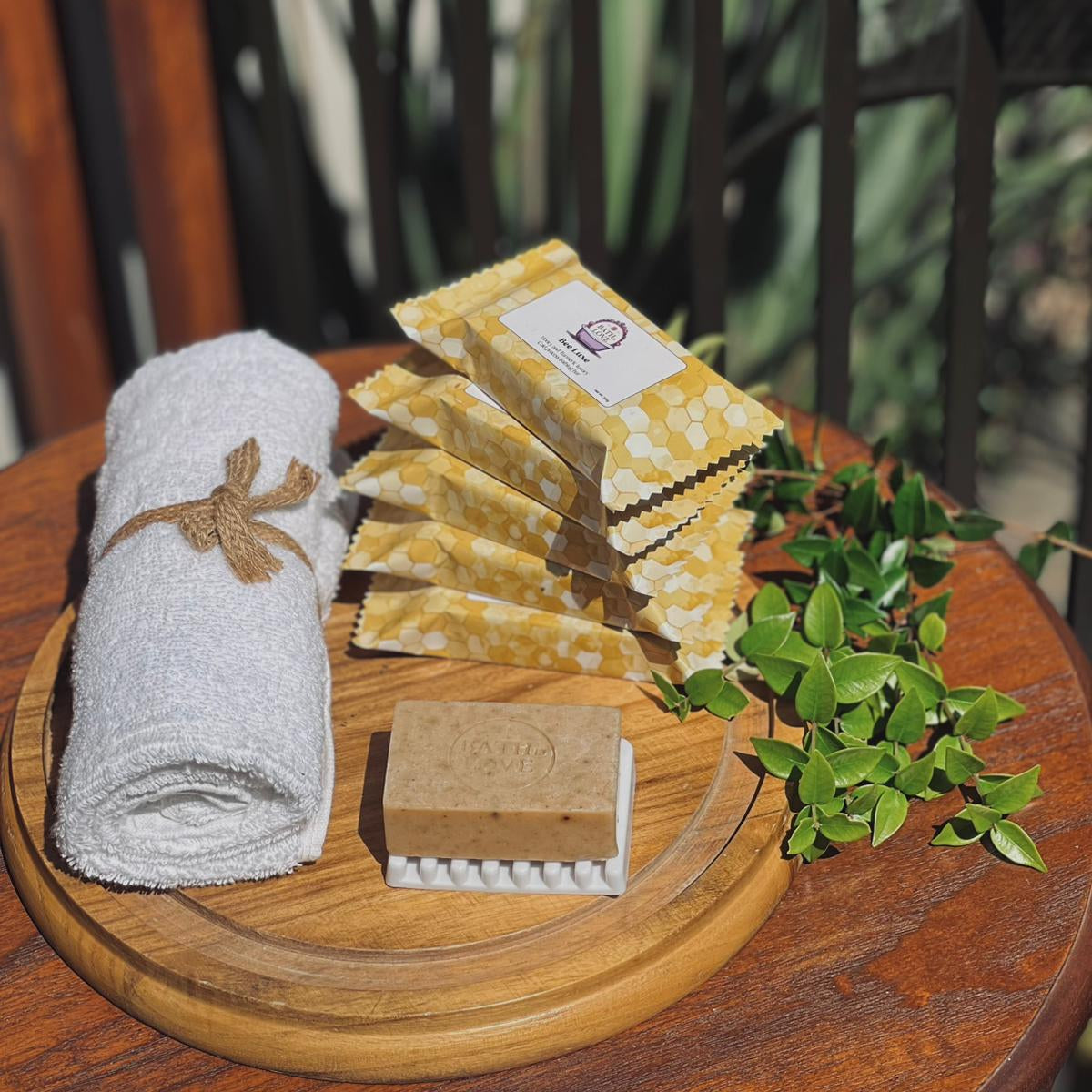 Set of soap bars, a rolled towel, and a bar of soap on a wooden tray with a natural background.