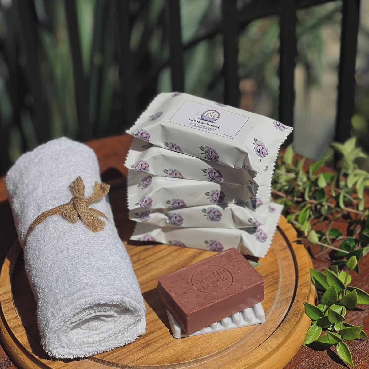 Set of soap bars and towels on a wooden tray with a natural background