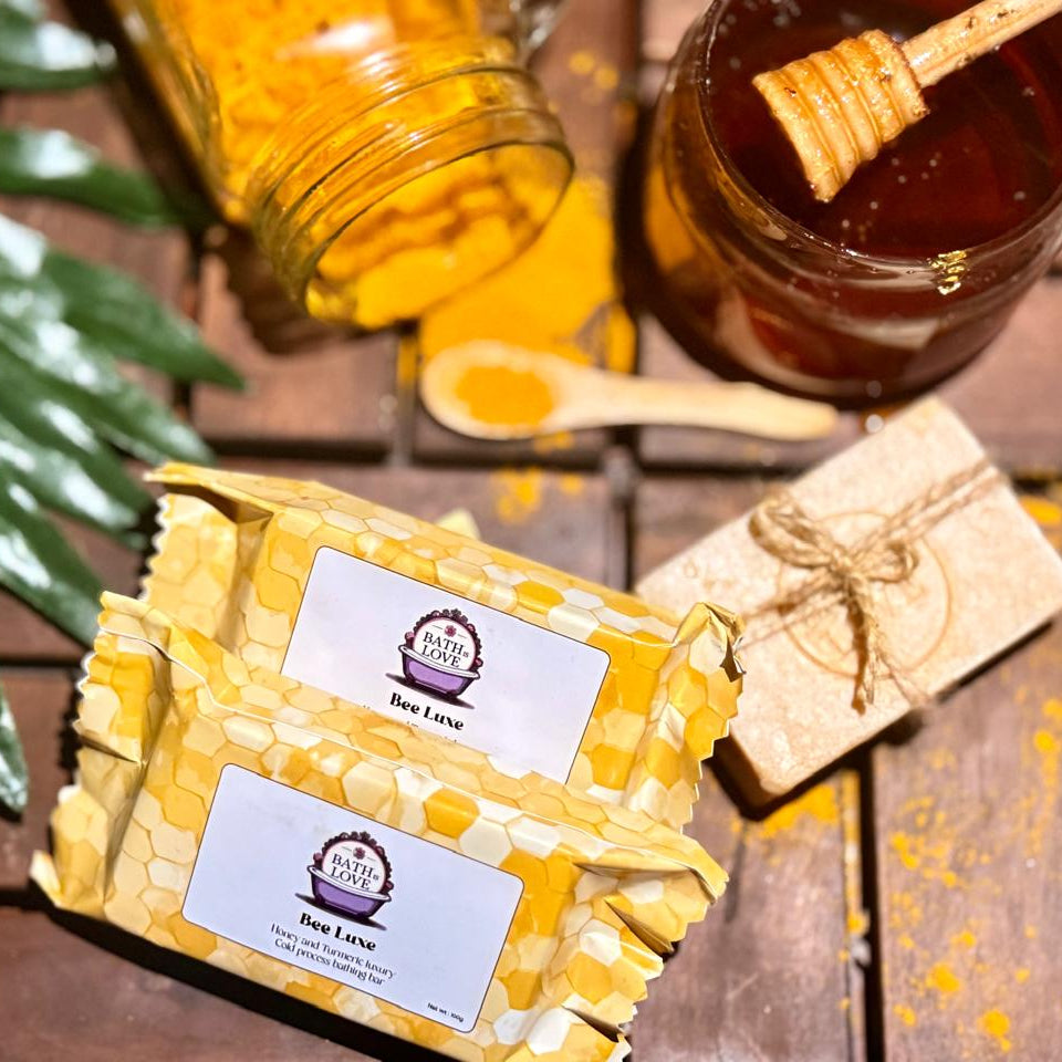 Two packages of honey labeled 'Bee Love' on a wooden surface with honeycomb and jars in the background.